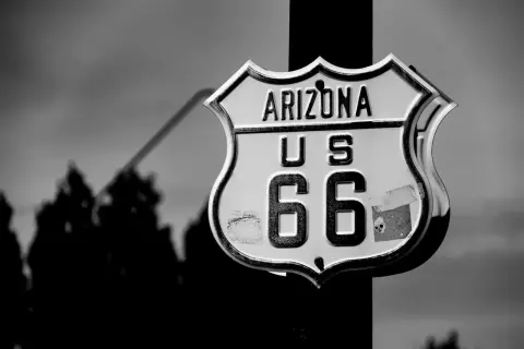 Znak Route 66 w Arizonie, z sylwetkami drzew w tle. Ikona amerykańskiej drogi.