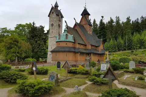 Drewniana świątynia Wang w Karkonoszach, otoczona cmentarzem i lasem.