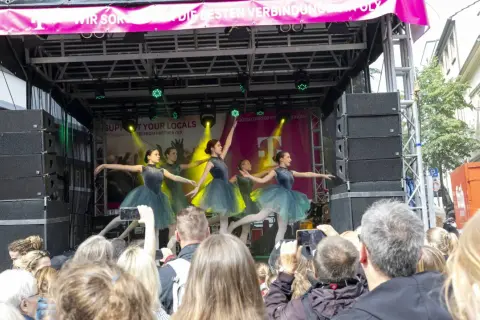 Ballettgruppe auf einer Bühne bei Veranstaltungen im Bergischen Land. Ein Publikum filmt die Darbietung.