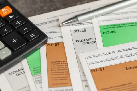 Kalkulator i długopis na dokumentach PIT-37 i PIT-36. Zastanawiasz się, kiedy pit 36, a kiedy 37?