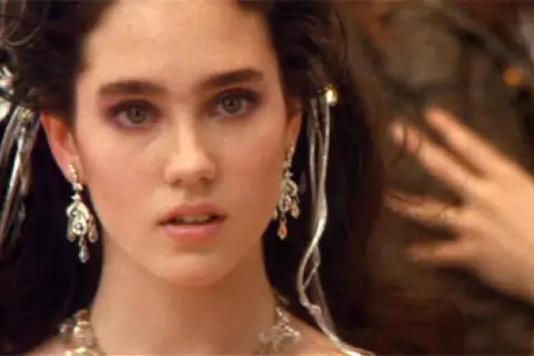 Jennifer Connelly w filmach, z burzą ciemnych włosów ozdobionych srebrnymi dodatkami i wyrazistym makijażem oczu.