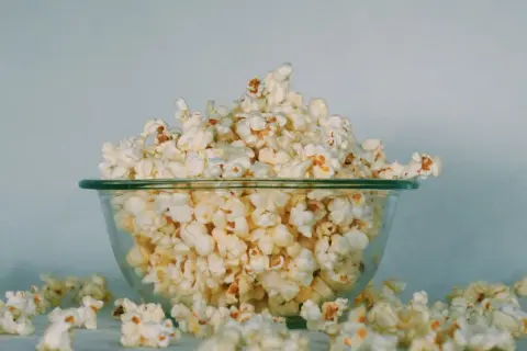 Miska pełna popcornu, rozsypanego wokół. Czy koty mogą jeść popcorn? To pytanie nurtuje wielu właścicieli.