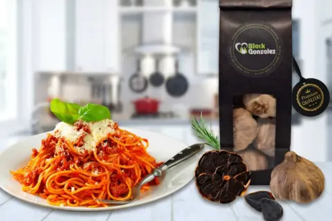 Spaghetti mit Tomatensoße, daneben eine Packung schwarzer Knoblauch und ganze Knoblauchzehen. Perfekt für schwarzer Knoblauch Rezepte.