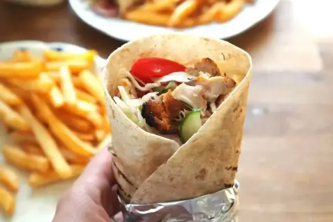 Pyszny kebab z kurczakiem, warzywami i frytkami na talerzu. Idealny posiłek na szybki lunch.
