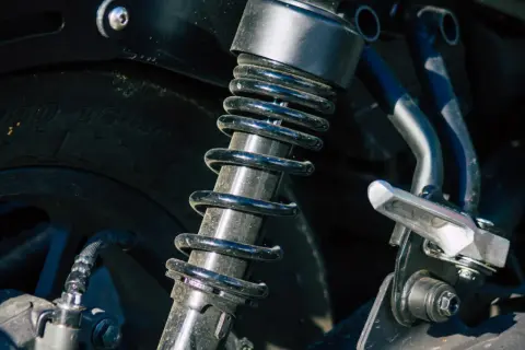 Sprężyna amortyzatora motocykla jest brudna i porysowana, co może wskazywać na uszkodzony amortyzator objawy.