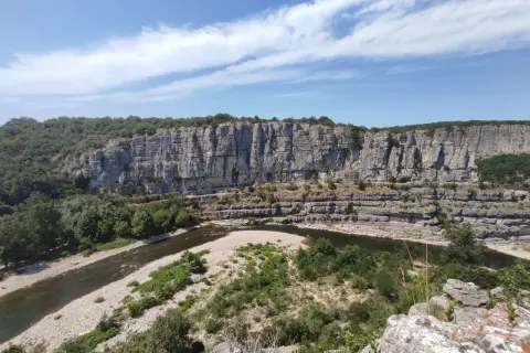 Un cirque de gens, des kayakistes profitent de la rivière au pied d'une falaise imposante.