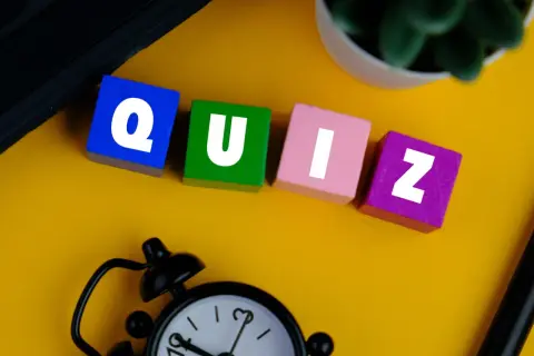 Kolorowe klocki z literami tworzą słowo QUIZ. Zegar i roślina sugerują, że czas sprawdzić swoją znajomość!