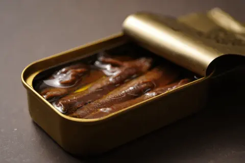 Latas doradas abiertas con las mejores anchoas del mundo, sumergidas en aceite.