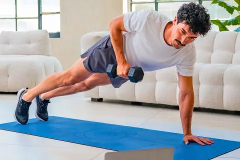 Uomo in posizione di plank con manubrio, esercizio per come migliorare la postura. Allenamento a casa.