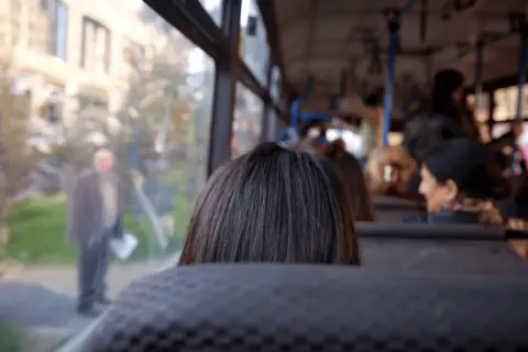 Widok z autobusu na ludzi i budynki. Codzienna podróż do pracy poza miejscem zamieszkania.