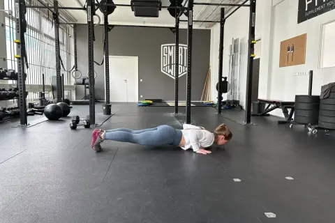 Frau macht Liegestütze im Fitnessstudio, ein Teil ihres plyometrischen Trainings.
