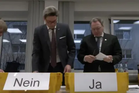 Männer bei einer Urabstimmung über einen Streik. Gelbe Boxen mit "Nein" und "Ja" stehen bereit.