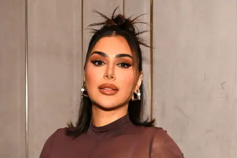 Kobieta z perfekcyjnym makijażem, jak po użyciu Huda Beauty Easy Blur, z błyszczącymi ustami i wyrazistymi oczami.