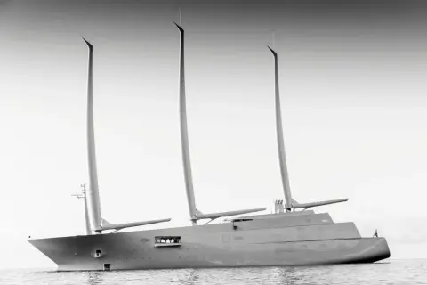 Un maestoso yacht a vela, un'opera di design firmata Philippe Starck, solca le acque con le sue tre imponenti vele.