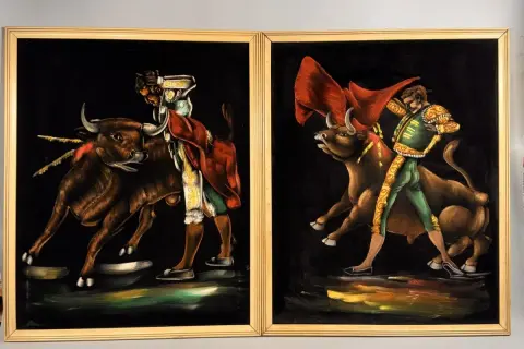 Two paintings by 1970s artists painters depict matadors facing bulls. The vibrant velvet art captures the drama of the bullfight.