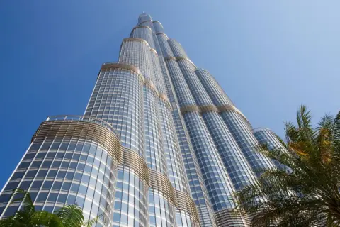 Burj Khalifa, najwyższy budynek na świecie, wznosi się ku błękitnemu niebu, otoczony palmami.