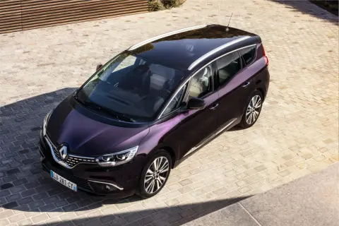Elegancki, fioletowy Renault Initiale z chromowanymi relingami dachowymi stoi na brukowanym podjeździe.
