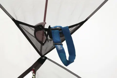 Okulary przeciwsłoneczne i latarka czołowa Petzl wiszą w siatkowej kieszonce namiotu MSR Elixir 2.
