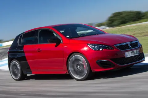 Czerwony Peugeot 308 GTI z czarnym tyłem na torze wyścigowym, dynamicznie pokonujący zakręt.