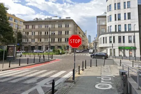 Widoczny znak stop na skrzyżowaniu ulic. Po prawej stronie budynek z napisem "Żabka".