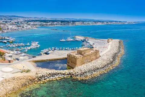 Zamek w Paphos, Cypr, nad turkusowym morzem. W tle port z łodziami i miasto. Idealne miejsce na wakacje, blisko lotniska.