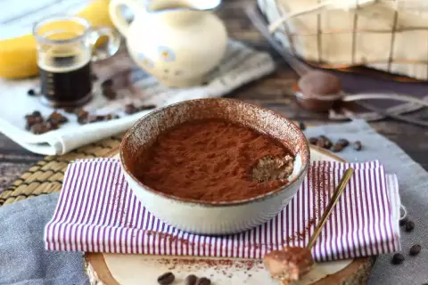 Schüssel mit Tiramisu Overnight Oats, bestäubt mit Kakao. Ein Löffel mit dem Dessert liegt daneben.