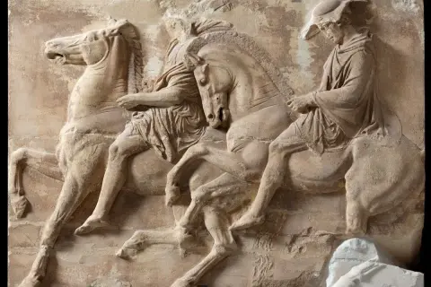 Starożytny grecki relief z Partenonu przedstawiający trzy postacie na koniach.