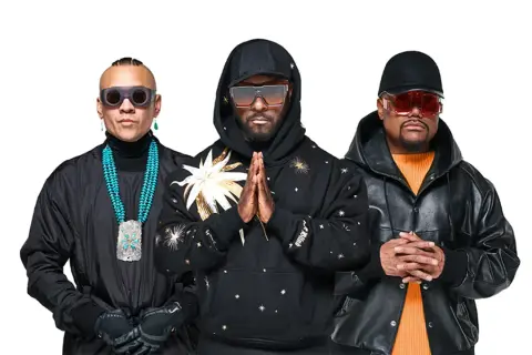 Les Black Eyed Peas, prêts pour un concert, posent ensemble. Will.i.am, Taboo et apl.de.ap arborent des lunettes de soleil stylées et des tenues audacieuses.