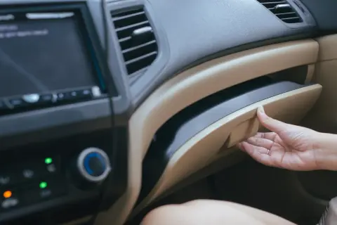 Mano apre il cassetto portaoggetti per recuperare i documenti obbligatori in auto.