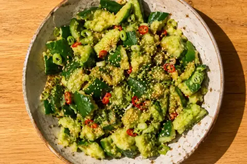 En skål med kinesisk gurksallad, toppad med sesamfrön, chili och salladslök. En fräsch och smakrik rätt.