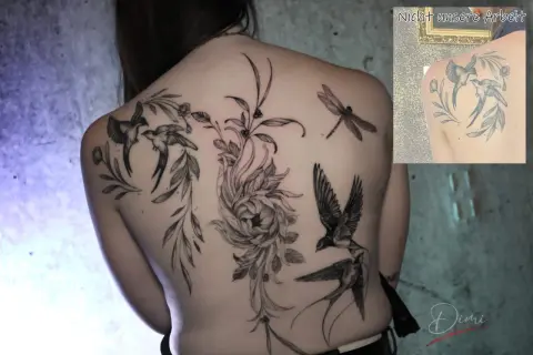 Ein detailliertes Backpiece Tattoo mit Schwalben, einer Libelle und einer großen Blume.