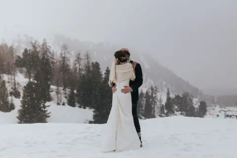 Un couple s'embrasse dans un paysage enneigé, un mariage thème montagne inoubliable.
