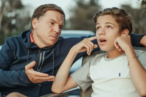 Padre parla con figlio adolescente, cercando di capire cosa fare quando i figli grandi litigano.