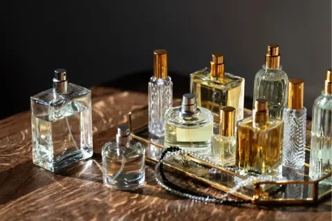 Kolekcja flakonów perfum, w tym Estee Lauder Modern Muse, na złotej tacy z biżuterią.