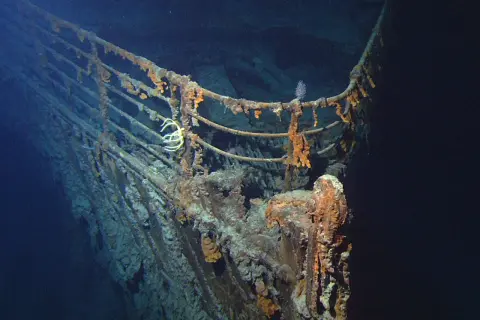 Proa del Titanic, una de las **titanic fotos reales**. Corrosión y vida marina cubren la barandilla oxidada en las profundidades del océano.