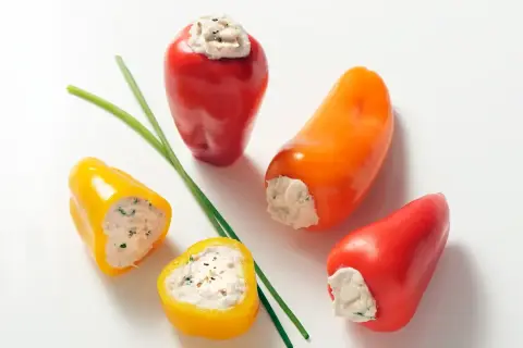 Des mini poivrons farcis colorés, garniture crémeuse et herbes fraîches, prêts à être dégustés.