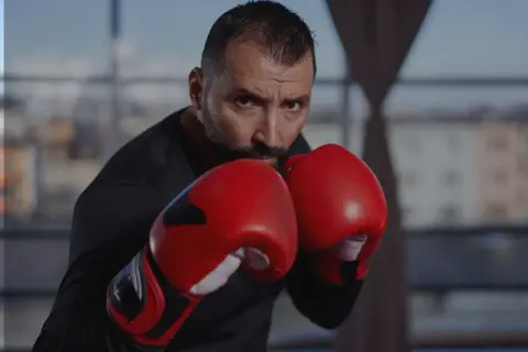 A focused boxer in red gloves, ready to implement his boxing strategy. His intense gaze suggests a well-thought-out plan.