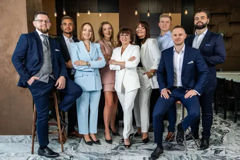Grupa profesjonalistów w eleganckich garniturach i kostiumach pozuje do zdjęcia.