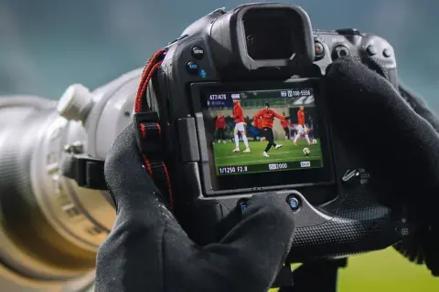 Aparat fotograficzny służy do uchwycenia dynamicznych momentów na boisku, jak ten piłkarz w akcji.