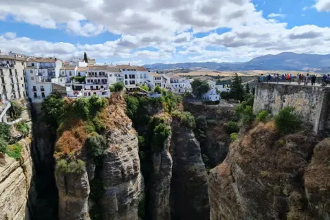 El mirador La Hoya del Tajo ofrece vistas espectaculares de casas blancas al borde de un profundo tajo, con gente admirando el paisaje.