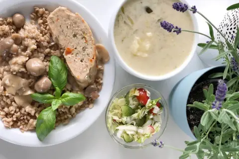 Kotlet mielony z kaszą, grzybami i surówką, obok miseczka zupy i lawenda.