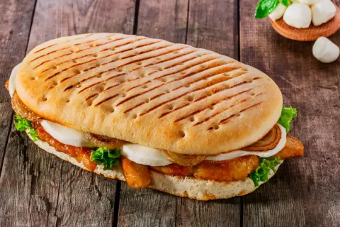 Ein gegrilltes Panini mit Hähnchen, Mozzarella, Salat und karamellisierten Zwiebeln. Ein leckeres panini rezept für jeden Tag.