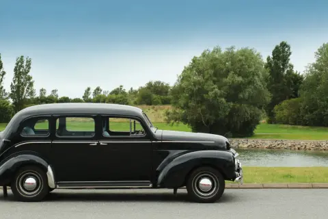 En svart, klassisk Volvo står parkerad vid en sjö. Denna gamla skönhet är en riktig sugga bil, perfekt för en tidlös resa.