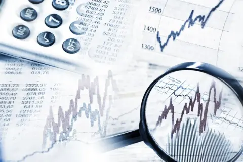 Analiza wykresów i tabel finansowych, kalkulator i lupa wskazują na analizę obligacji korporacyjnych emisji.