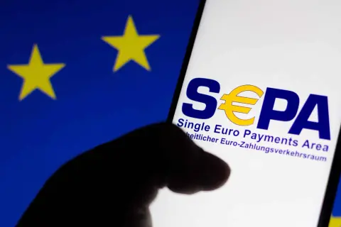 Logo SEPA na ekranie telefonu, na tle flagi UE. Czy w Albanii można płacić euro? SEPA to obszar jednolitej płatności w euro.