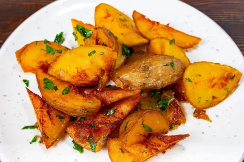 Pommes de terre rôties, coupées en quartiers et parsemées de persil frais. Une recette simple et savoureuse pour un accompagnement parfait.