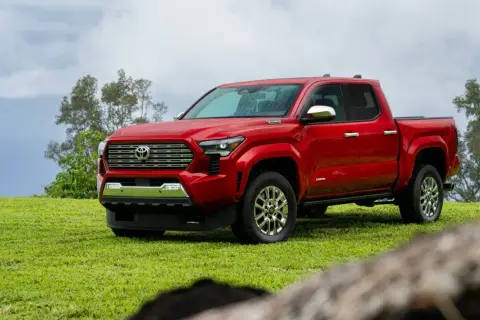 Czerwona Toyota Tacoma na zielonej trawie, gotowa na przygodę.