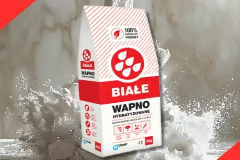 Białe wapno hydratyzowane w opakowaniu, otoczone chmurą białego pyłu. Idealne do prac budowlanych.