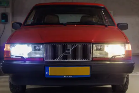 Czerwone Volvo z włączonymi światłami. Czy ledy mogą się zapalić? Tak, te świecą jasno, oświetlając parking.