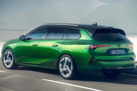 Zielony Opel Astra kombi, jeden z nowoczesnych opel modele, pędzi po drodze.